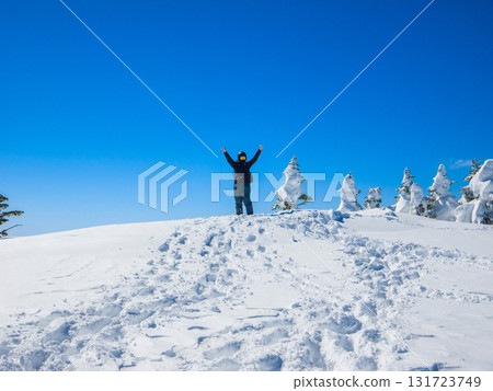 Snowboarder cheering with arms outstretched on the summit of a snowy mountain (Yokoteyama, Shiga Kogen, Nagano Prefecture) Snowboarder cheering with arms outstretched on the summit of a snowy mountain (Yokoteyama, Shiga Kogen, Nagano Prefecture) 131723749