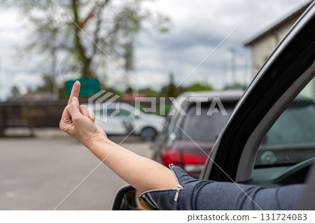 woman shows obscene gesture from a car, rude and furious driver giving middle finger to car behind 131724083