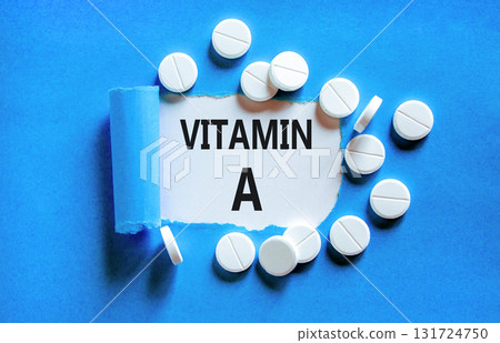 Vitamin A symbol. Concept words Vitamin A on beautiful white paper. White pills tablets. Beautiful blue background. Medical healthy lifestyle Vitamin A concept. Vitamin A symbol. Concept words Vitamin A on beautiful white paper. White pills tablets. Beautiful blue background. Medical healthy lifestyle Vitamin A concept. 131724750