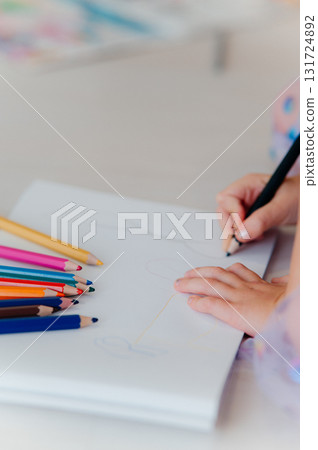 A Child Engaging in Drawing with Colored Pencils on a Completely Blank Page to Express Creativity 131724892