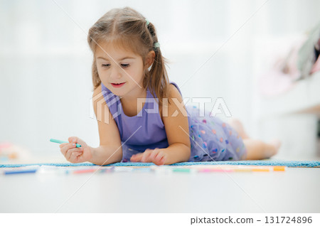 A joyful Child enjoying Artistic Playtime with Colorful Markers spread across the Floor 131724896