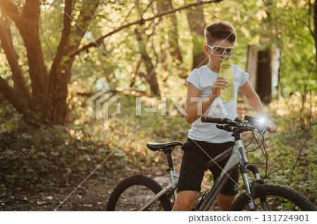 A Young Biker Indulging in a Refreshing Drink While Enjoying the Beauty of Nature A Young Biker Indulging in a Refreshing Drink While Enjoying the Beauty of Nature 131724901