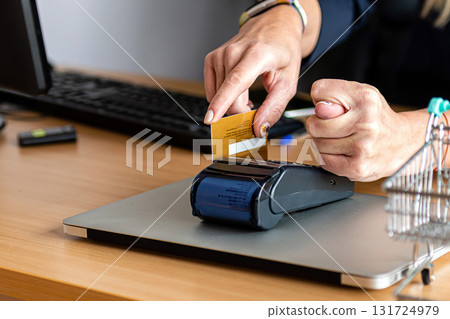 a woman uses a payment card terminal to shop online and shows a fig with his other hand a woman uses a payment card terminal to shop online and shows a fig with his other hand 131724979