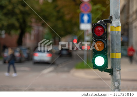 view of city traffic with traffic lights, in the foreground a semaphore with a green light, closeup 131725010