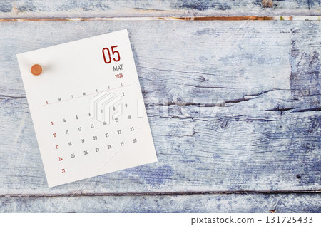 May 2026 monthly calendar and wooden push pin on blue wooden background. May 2026 monthly calendar and wooden push pin on blue wooden background. 131725433