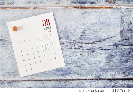 August 2026 monthly calendar and wooden push pin on blue wooden background. 131725500