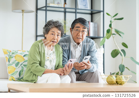 老夫婦在客廳裡看智能手機 131725526