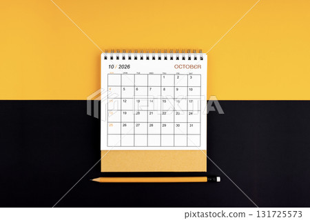 Top view of October 2026 desk calendar and pencil on yellow and black color. Top view of October 2026 desk calendar and pencil on yellow and black color. 131725573