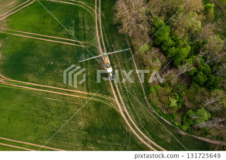 aerial view of the tractor spraying the chemicals on the large green field aerial view of the tractor spraying the chemicals on the large green field 131725649