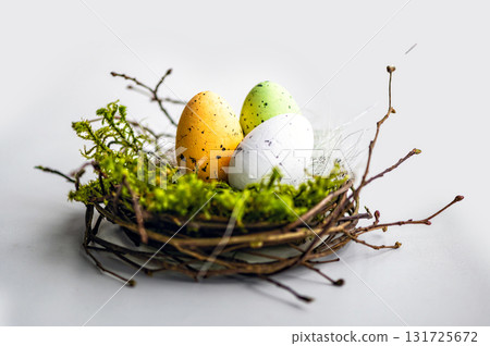 nest with colored Easter eggs isolated on a light defocused background, easter decorations, close-up nest with colored Easter eggs isolated on a light defocused background, easter decorations, close-up 131725672