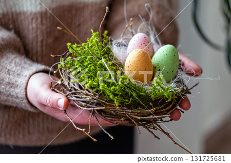 woman hands holding painted easter eggs in a small bird nest woman hands holding painted easter eggs in a small bird nest 131725681