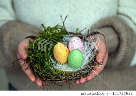 woman hands holding painted easter eggs in a small bird nest woman hands holding painted easter eggs in a small bird nest 131725682