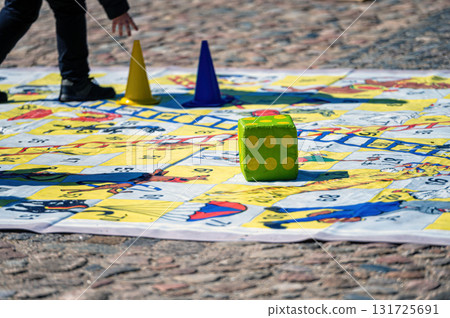 people outdoors on a sunny day on the pavement playing an enlarged board game people outdoors on a sunny day on the pavement playing an enlarged board game 131725691