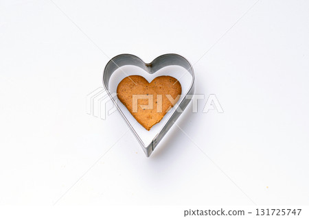 Heart-shaped cookie cutter and freshly baked gingerbread, isolated, copy space, closeup Heart-shaped cookie cutter and freshly baked gingerbread, isolated, copy space, closeup 131725747