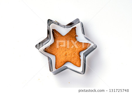Star-shaped cookie cutter and freshly baked gingerbread, isolated, copy space, closeup Star-shaped cookie cutter and freshly baked gingerbread, isolated, copy space, closeup 131725748