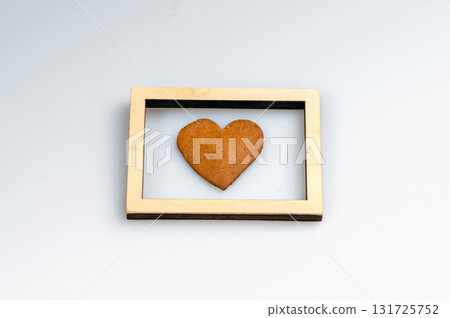heart-shaped gingerbread and wooden frame isolated on a white background, closeup heart-shaped gingerbread and wooden frame isolated on a white background, closeup 131725752