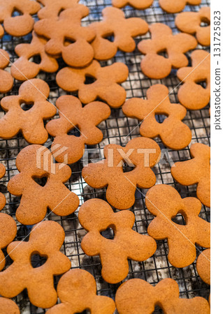 Freshly baked gingerbread cookies find their place on a cooling wire rack in a modern white kitchen, filling the air with festive aromas. Freshly baked gingerbread cookies find their place on a cooling wire rack in a modern white kitchen, filling the air with festive aromas. 131725823