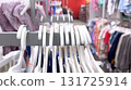 A retail clothing rack filled with children's garments on white hangers is displayed in a bright store aisle. The image focuses on neat arrangement and indoor retail environment. 131725914