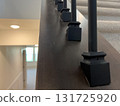 Angled stair rail with black spindles overlooking a hallway below. The image highlights clean construction, modern materials, and soft natural lighting. 131725920
