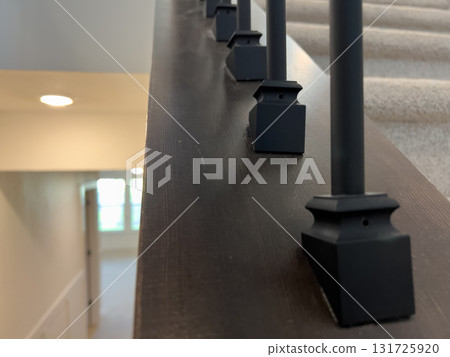 Angled stair rail with black spindles overlooking a hallway below. The image highlights clean construction, modern materials, and soft natural lighting. Angled stair rail with black spindles overlooking a hallway below. The image highlights clean construction, modern materials, and soft natural lighting. 131725920
