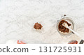 Close-up view of a ball of Chocolate Ginger Sugar Cookie Dough wrapped in plastic, prepared for chilling on a marble countertop to firm up before baking. 131725931