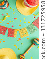 Overhead view of vibrant Mexican fiesta decorations including paper banners, sombreros, and maracas on a mint green background with confetti. Ideal for Cinco de Mayo, party invitations, or holiday 131725958
