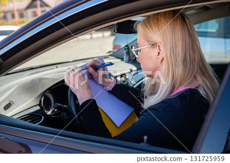 middle aged blonde business woman in glasses in car working with documents, mobile technology concept 131725959