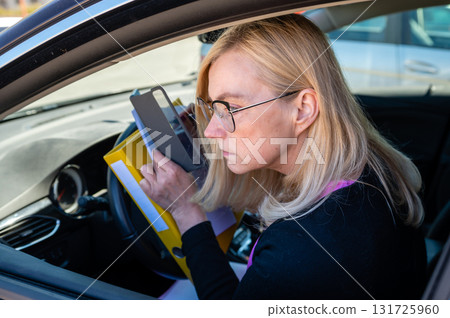 middle aged blonde business woman in glasses in car working with documents, mobile technology concept middle aged blonde business woman in glasses in car working with documents, mobile technology concept 131725960