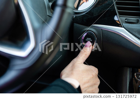 Woman hand pushing on car engine start-stop button. Modern car interior, closeup 131725972