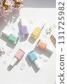 A flat lay arrangement shows pastel colored nail polish bottles with small flowers and brushes. The bright white surface highlights the seasonal spring theme. The image emphasizes style and creativity 131725982