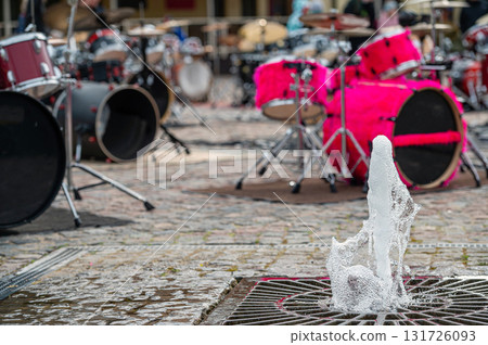 closeup of a fountain on the background of a defocused paved area with many drum kits 131726093