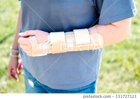 A woman's hand with a beige brace in a summer park, close-up 131727121