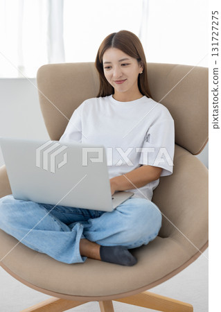 一位年輕女子坐在椅子上，在電腦上工作 131727275