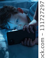 Child Staring at Smartphone in Bed at Night 131727297