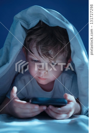 Child using smartphone in bed late at night 131727298