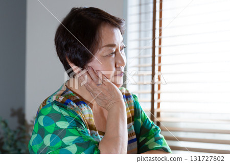 一位老年婦女的側面像，她靠著下巴，直視前方 131727802
