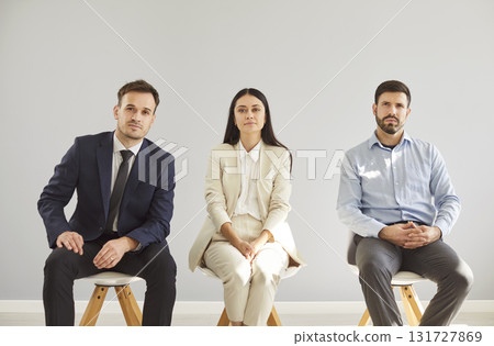Group Portrait Of Business Team Sitting On Chairs In Grey Background Group Portrait Of Business Team Sitting On Chairs In Grey Background 131727869