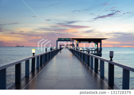 Walkway extending into calm sea at twilight. 131728379