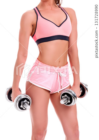 Slim girl in pink shorts and pink top doing exercise with dumbbells. Fitness and healthy lifestyle concept. Isolated on the white background Slim girl in pink shorts and pink top doing exercise with dumbbells. Fitness and healthy lifestyle concept. Isolated on the white background 131728990