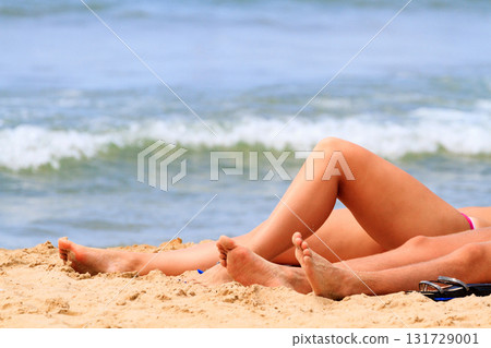 Woman and may lay on a sandy beach by the sea or ocean. Summer vacations concept Woman and may lay on a sandy beach by the sea or ocean. Summer vacations concept 131729001