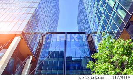 Glass office building surrounded with green trees. Eco-friendly office building. Sustainable architecture of city reducing heat carbon dioxide modern city environment. Glass office building surrounded with green trees. Eco-friendly office building. Sustainable architecture of city reducing heat carbon dioxide modern city environment. 131729319