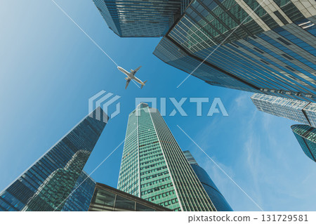 Modern glass skyscrapers on a clear day and passenger plane flies over Modern glass skyscrapers on a clear day and passenger plane flies over 131729581