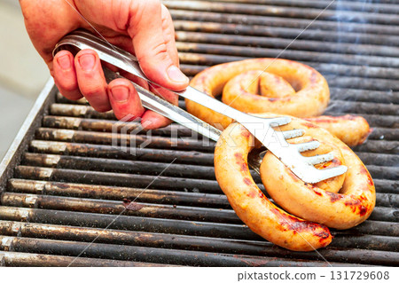 Male hand with a fork touching meat on the grill 131729608
