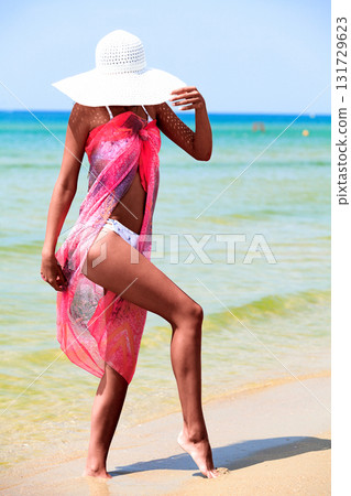 Slim tanned woman posing on a sea beach Slim tanned woman posing on a sea beach 131729623