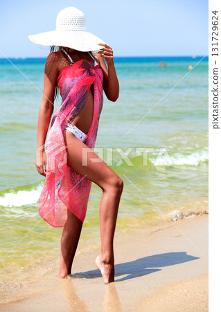 Slim tanned woman posing on a sea beach Slim tanned woman posing on a sea beach 131729624