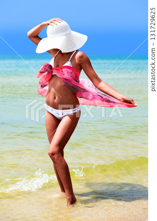 Slim tanned woman posing on a sea beach Slim tanned woman posing on a sea beach 131729625