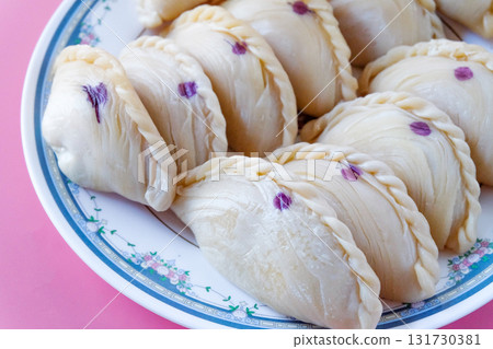 Raw Curry puff snack made from puff pastry skin and filled with curry chicken in dish. 131730381