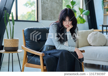 Unhappy upset tired young woman sitting on chair at home 131730397