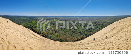 La Teste-de-Buch, Arcachon Bay, France - May 09, 2024: panoramic view of the immense Dune of Pilat, the tallest sand dune in Europe. Massive golden sandbanks dotted with multiple tourists 131730596