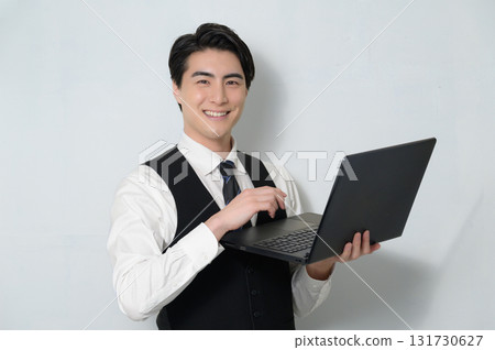 A man looking at the camera while holding a laptop on a white background A man looking at the camera while holding a laptop on a white background 131730627